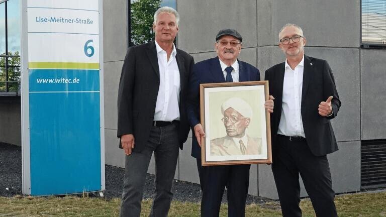 From left to right: Dr Olaf Hollricher (WITec Managing Director Research and Development), Professor Dr Wolfgang Kiefer with the historical portrait of C.V. Raman, Dr Joachim Koenen (WITec Managing Director).