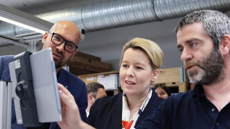 Production employee Eloi Yepes-Asens (right) shows Franziska Giffey and Micheal Biel the electronic production guide (Credit: Knauer)