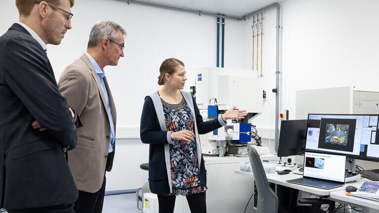 Anna Steyer, Cryo-tomography Specialist at EMBL IC explains service workflows offered in correlative light and electron microscopy under cryogenic conditions to Michael Albiez (Head of ZEISS Research Microscopy Solutions) and Herbert Schaden (Head of Global Academia Key Account Management at ZEISS Research Microscopy Solutions). Credit: Stuart Ingham/EMBL