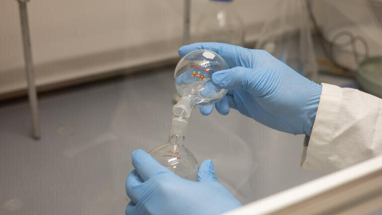 A researcher demonstrates some of the equipment used to synthesize the new nanoparticles. Credit: Bella Ciervo, Penn Engineering